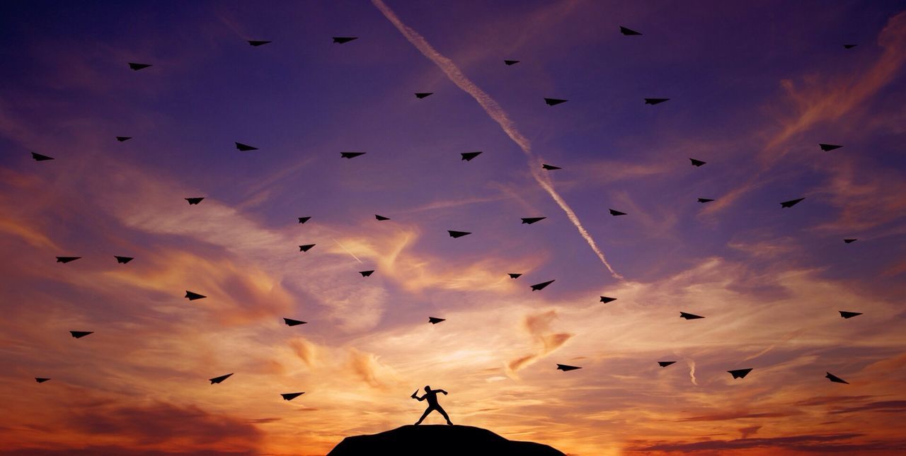 Silhouette of man throwing paper airplanes