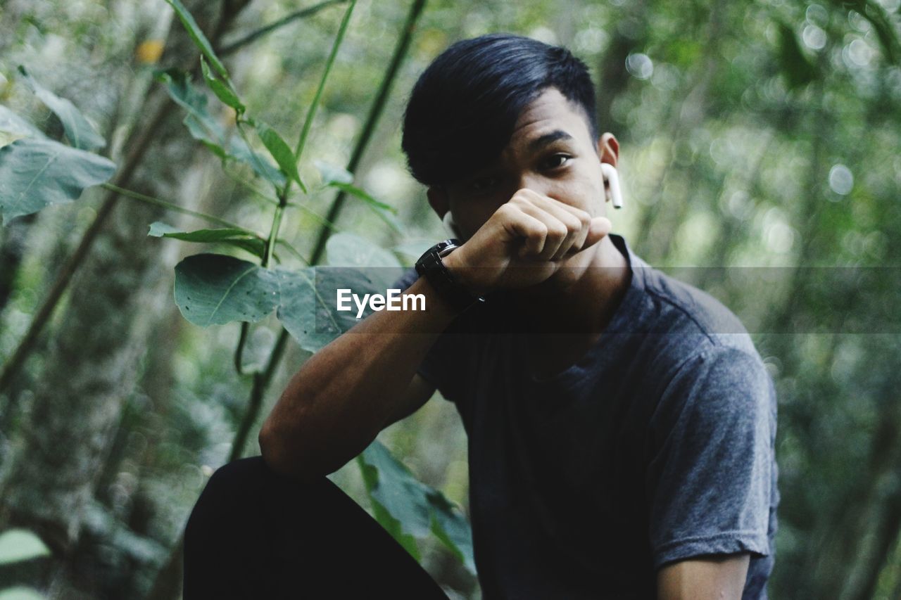 Portrait of young man sitting at forest