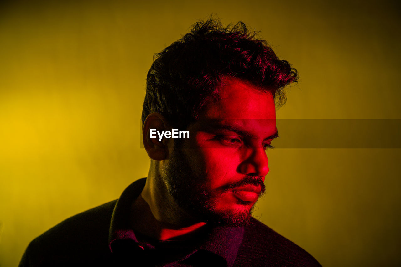 Close-up of thoughtful man against yellow background