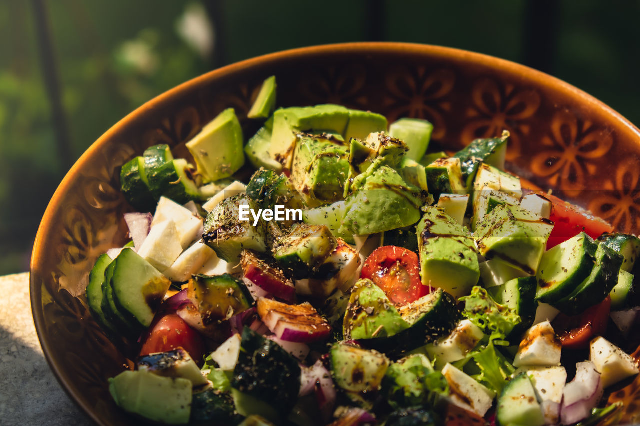 Avocado mix of vegetables salad in daytime outdoors. fresh salad with tomatoes, avocado, lettuce