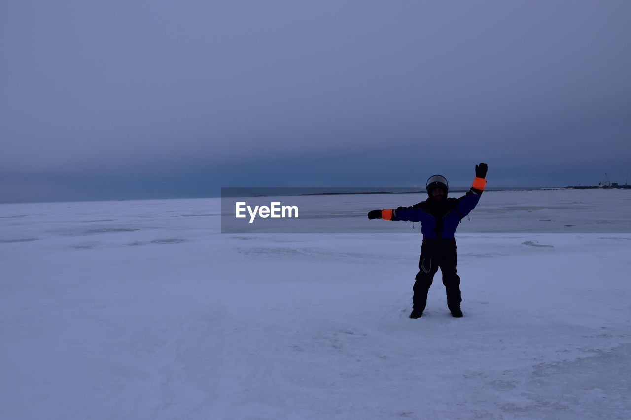 Full length of woman walking on snow covered field against clear sky