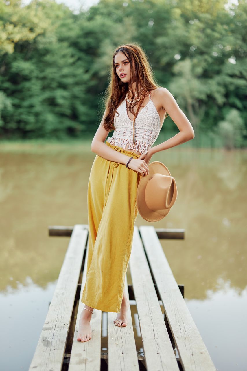 side view of young woman standing against lake