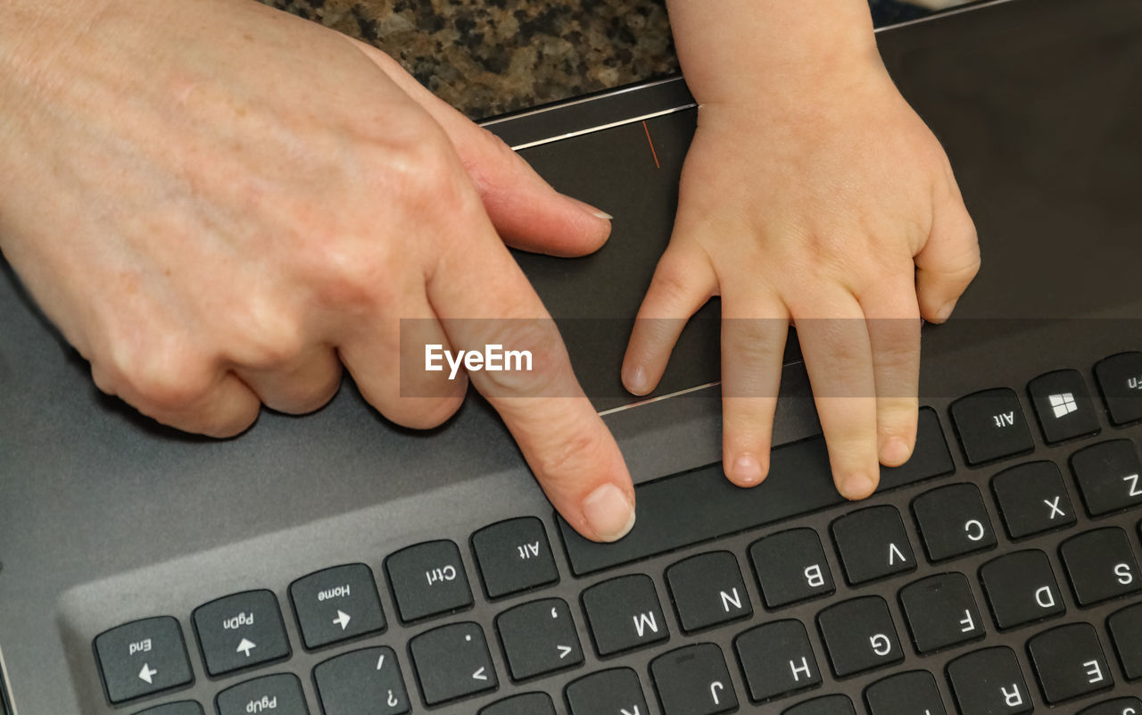 Cropped hands of people using laptop keyboard
