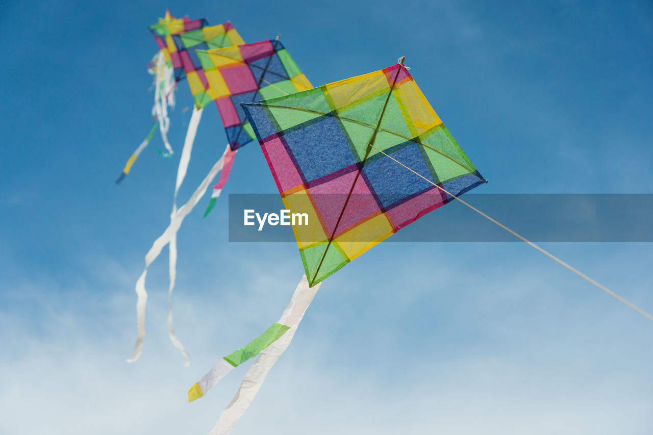 Low angle view of kites flying against sky