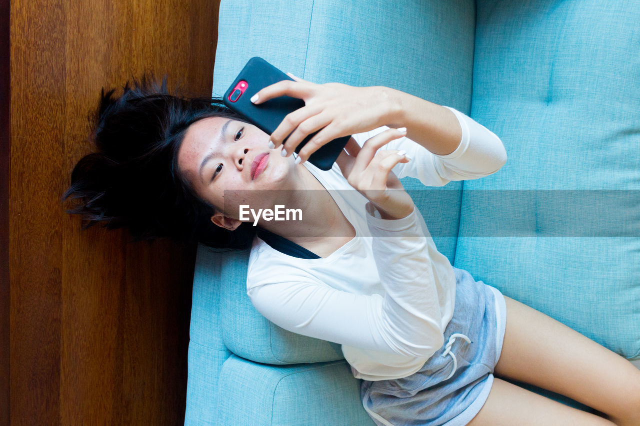 Asian teenage girl lay down using mobile phone