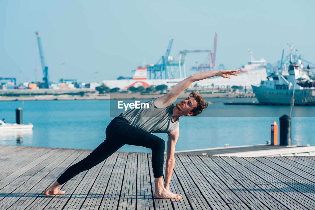 YOUNG WOMAN ON PIER AGAINST SEA AGAINST SKY