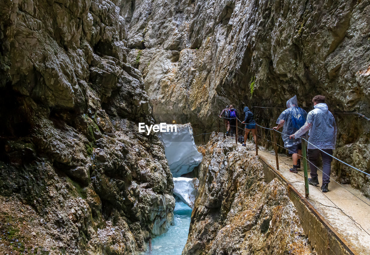 GROUP OF PEOPLE ON ROCKS BY MOUNTAIN