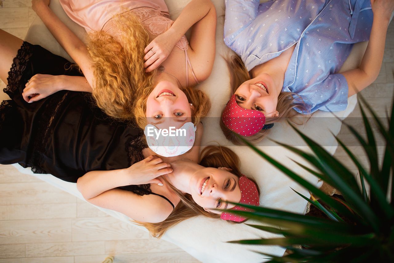 HIGH ANGLE VIEW OF SIBLINGS RELAXING ON BED