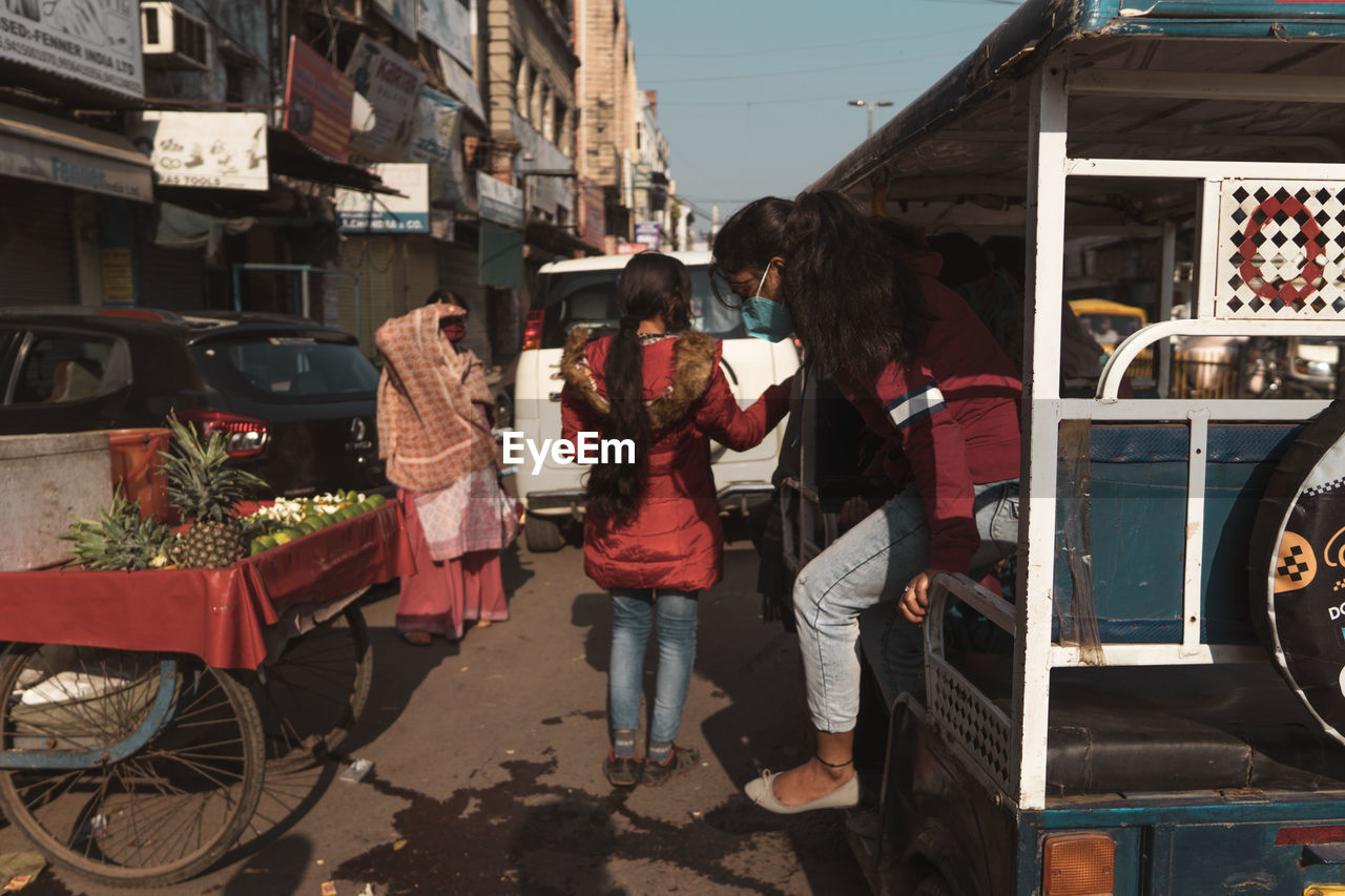 REAR VIEW OF PEOPLE ON STREET IN CITY