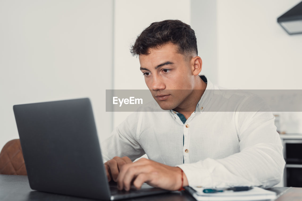 young man using laptop while sitting at desk in office
