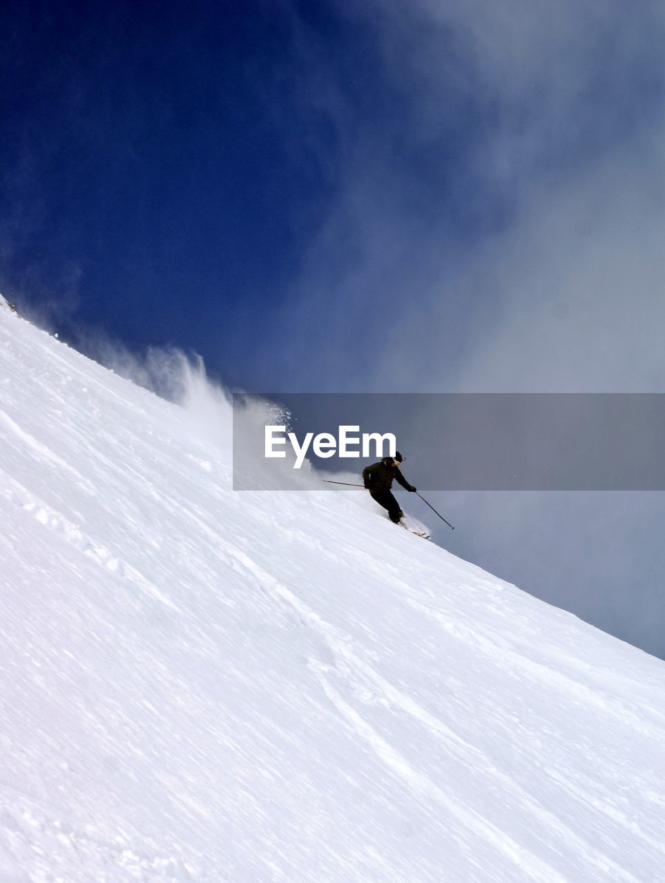 Person skiing on snow covered slope against sky