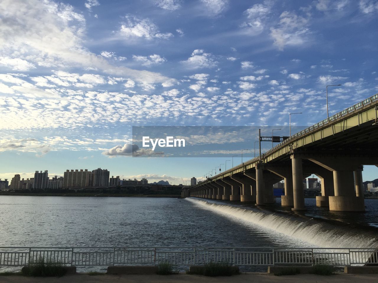 Bridge over river in city against sky