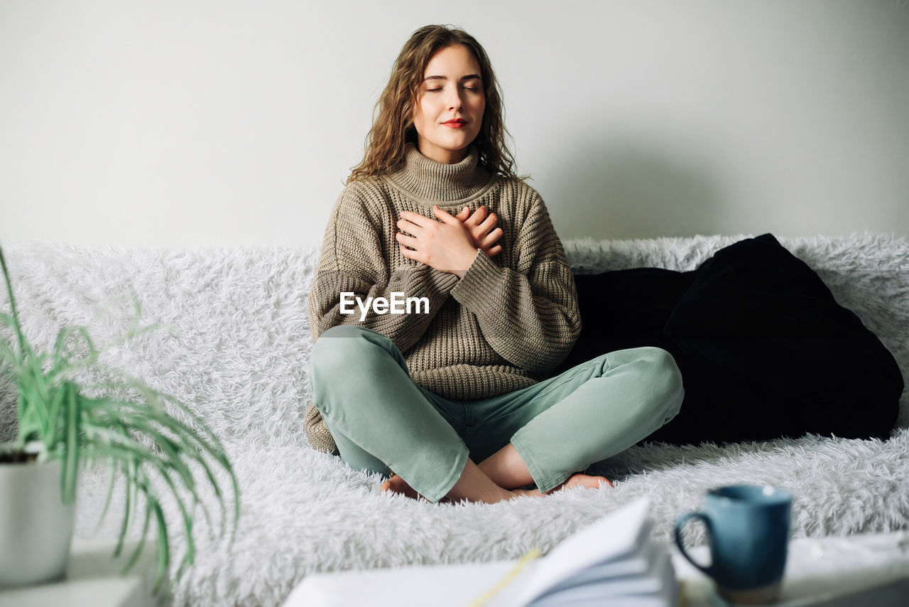 Relaxation woman practicing pranayama in lotus position on bed