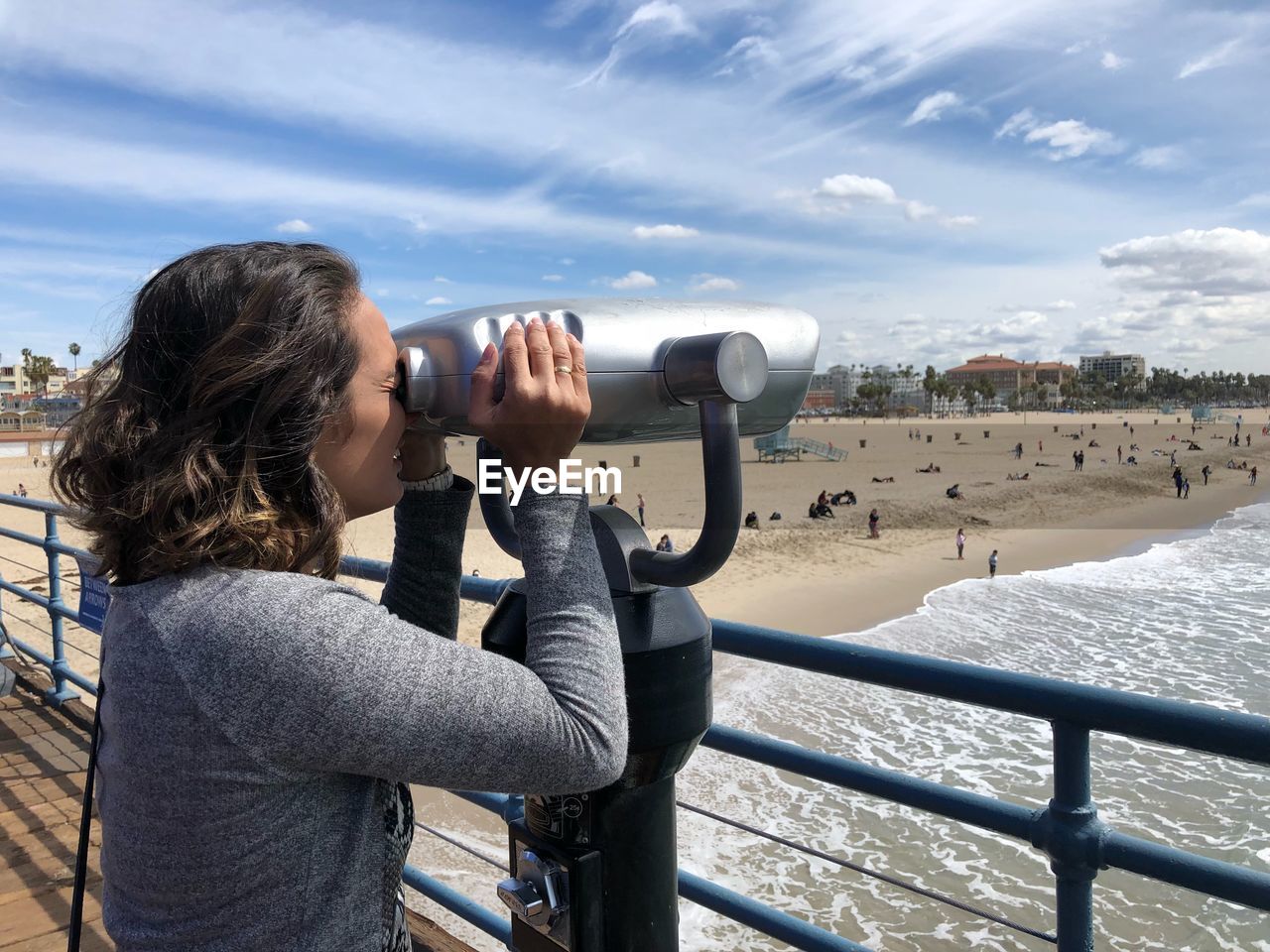 Woman looking at beach through coin-operated binoculars