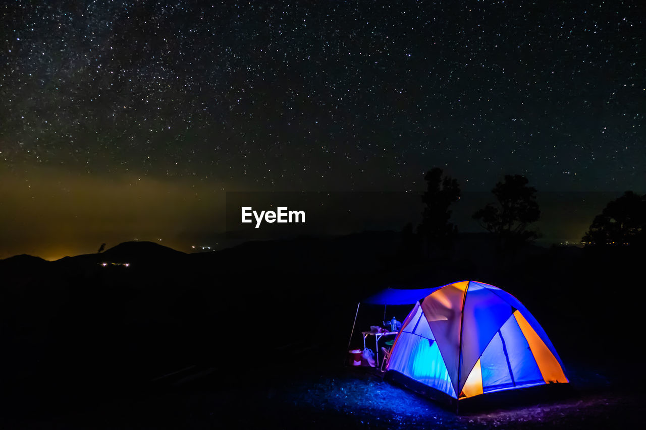 Illuminated tent on land against sky at night