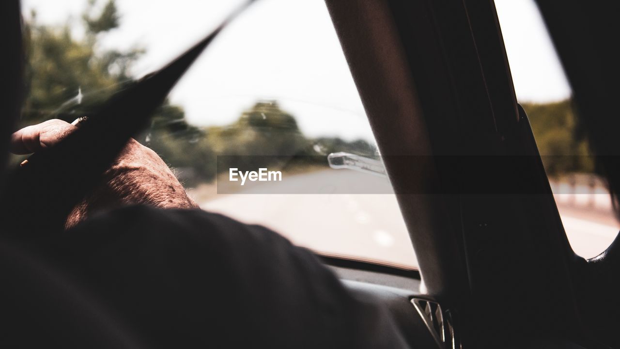 Cropped hand of man smoking cigarette in car