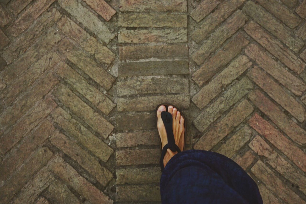 LOW SECTION OF WOMAN STANDING ON TILED FLOOR