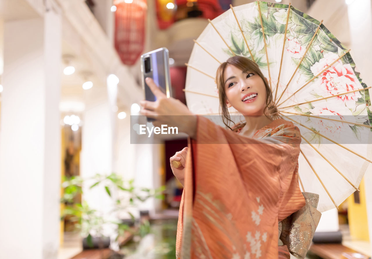 Smiling woman wearing traditional clothing taking selfie outdoors