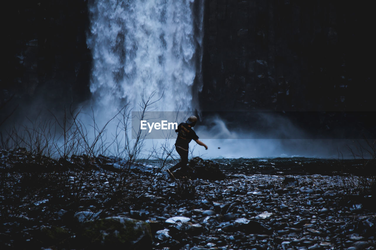 Man standing by waterfall in forest