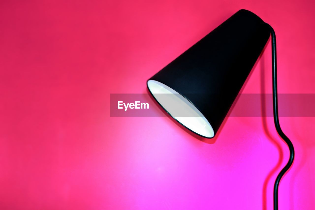 Close-up of illuminated floor lamp against pink background