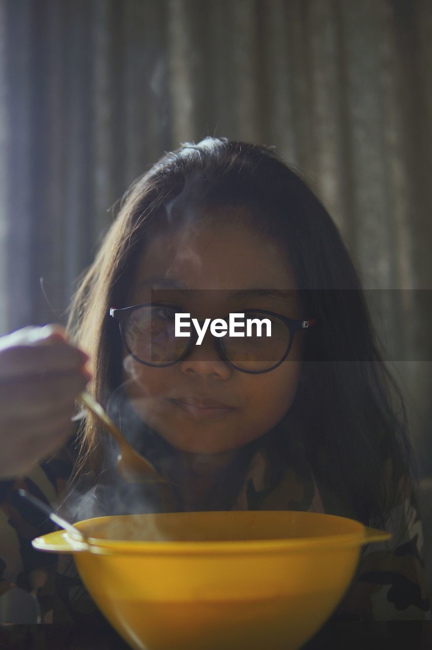 Close-up portrait of girl having food while sitting on table at home