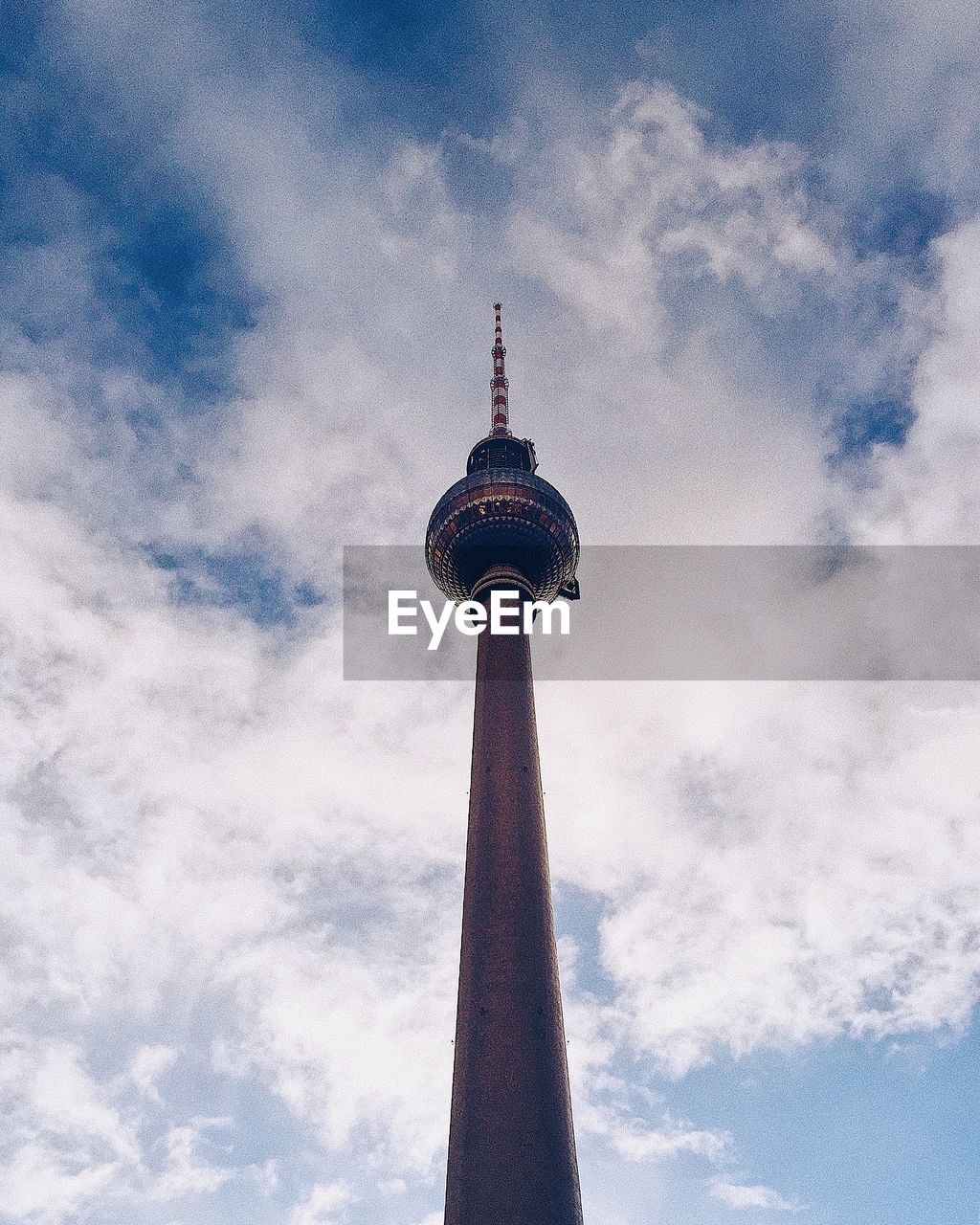 Low angle view of communications tower against cloudy sky