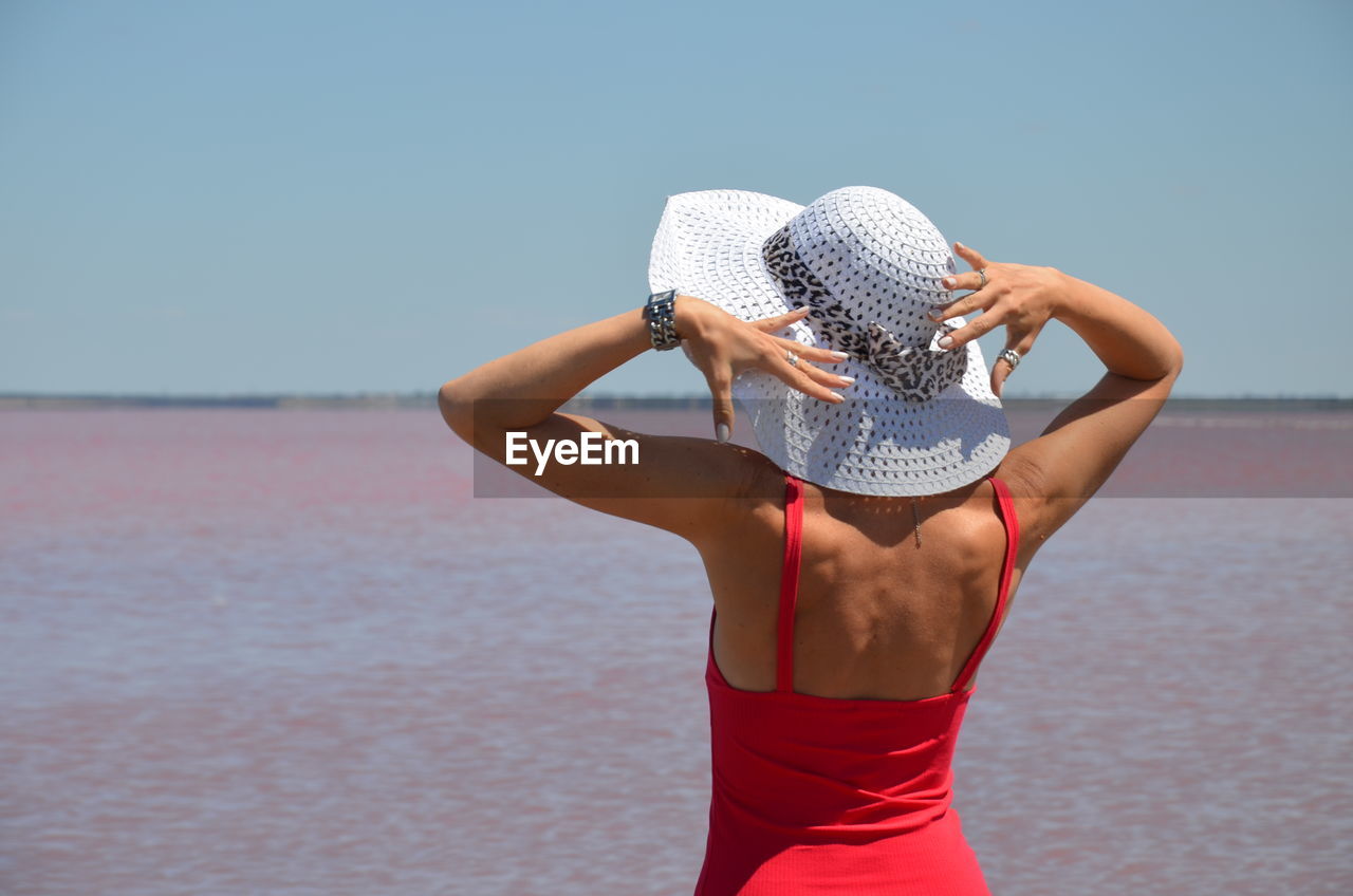 Midsection of woman standing by sea against sky