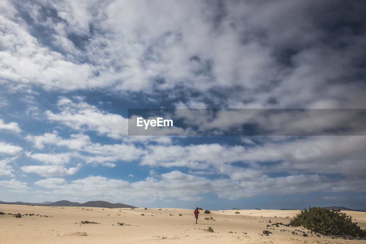 Woman walking on desert against sky