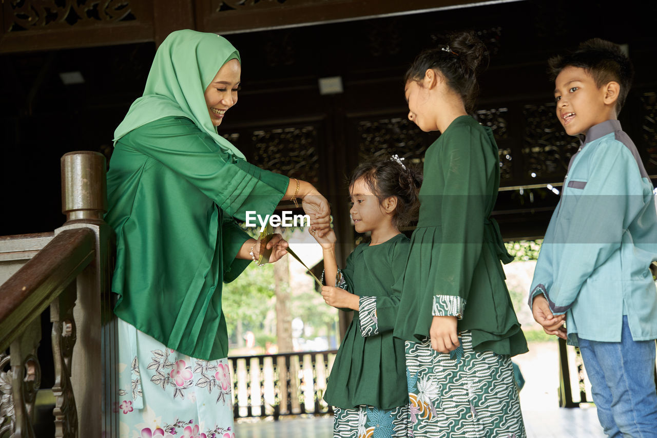 Daughter and son standing in a row greeting mother ask forgiveness during ramadan festival 