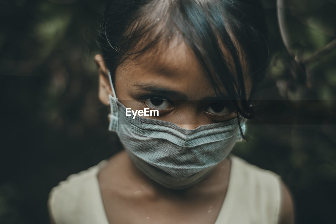 Close-up portrait of girl wearing mask standing outdoors