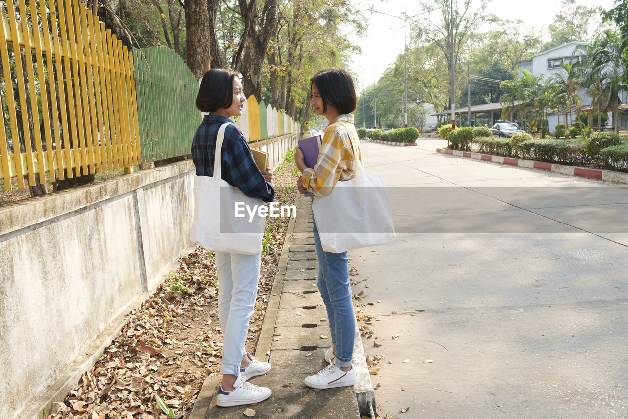 Side view of girls talking while standing on road