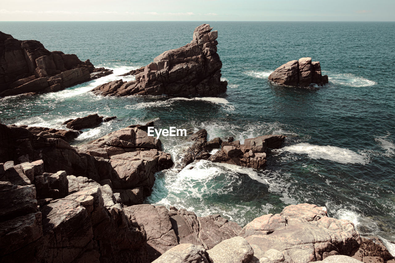 Scenic view of rocks in sea against sky