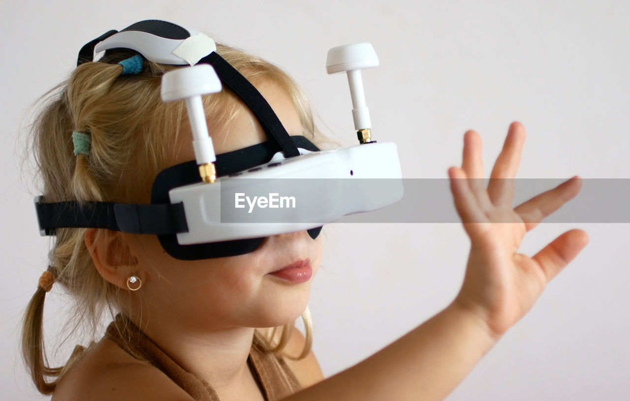 Close-up of girl wearing virtual reality simulator against wall