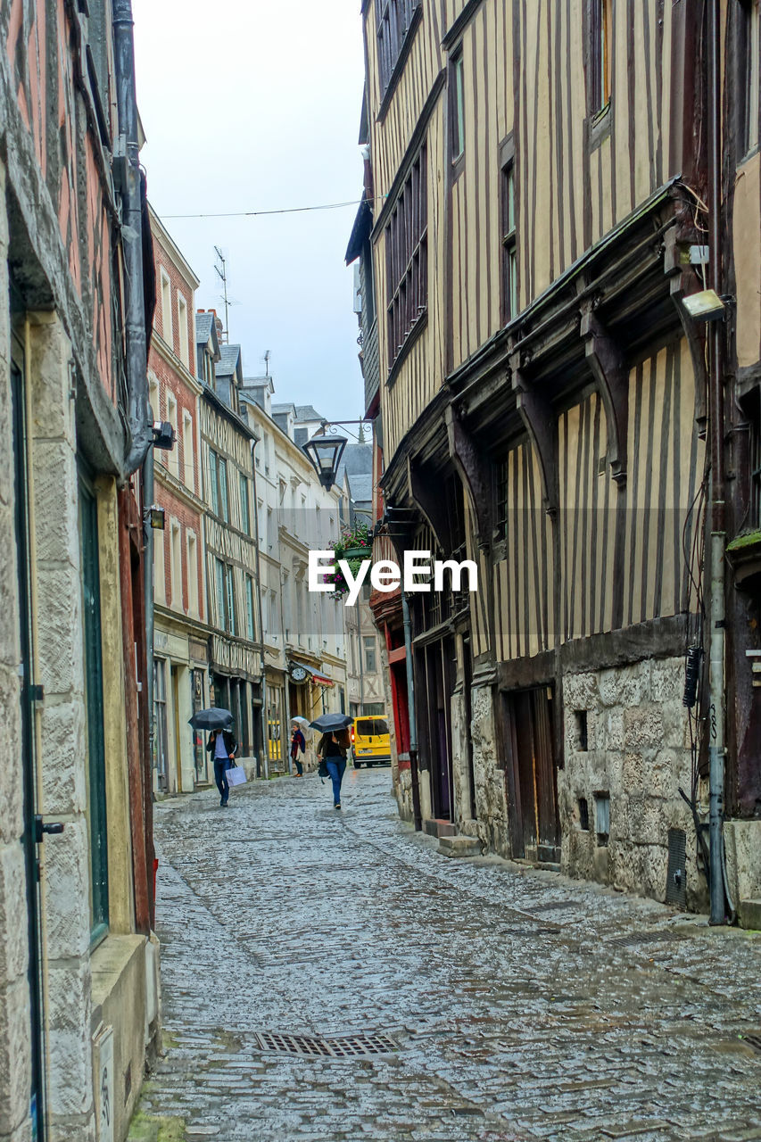 PEOPLE WALKING ON STREET AMIDST BUILDINGS