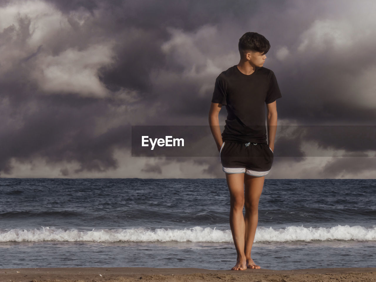 Full length of teenage boy standing on shore at beach