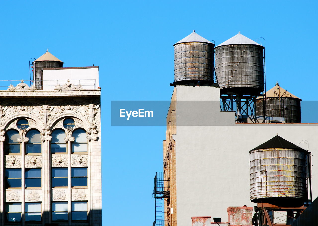 Low angle view of water tanks on apartment buildings against clear sky