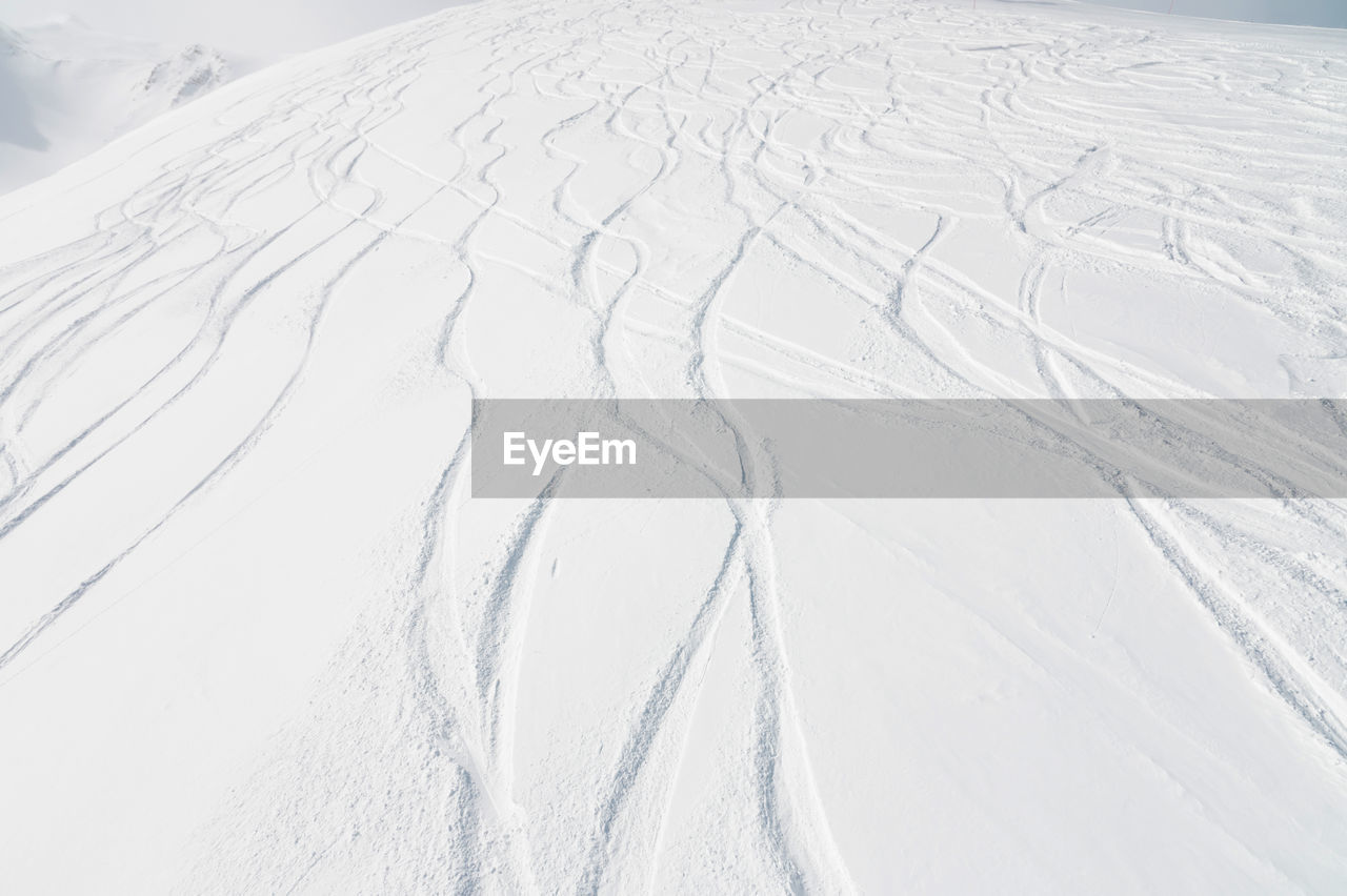 Top view of the snow-covered slope of the mountain, traces from skiers and snowboarders, no people