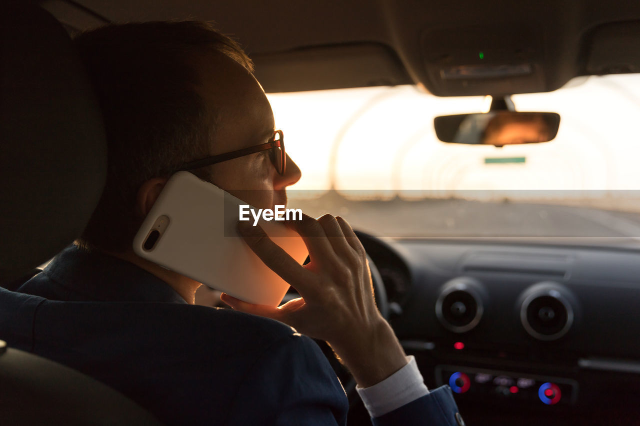 Businessman talking on smart phone while driving car