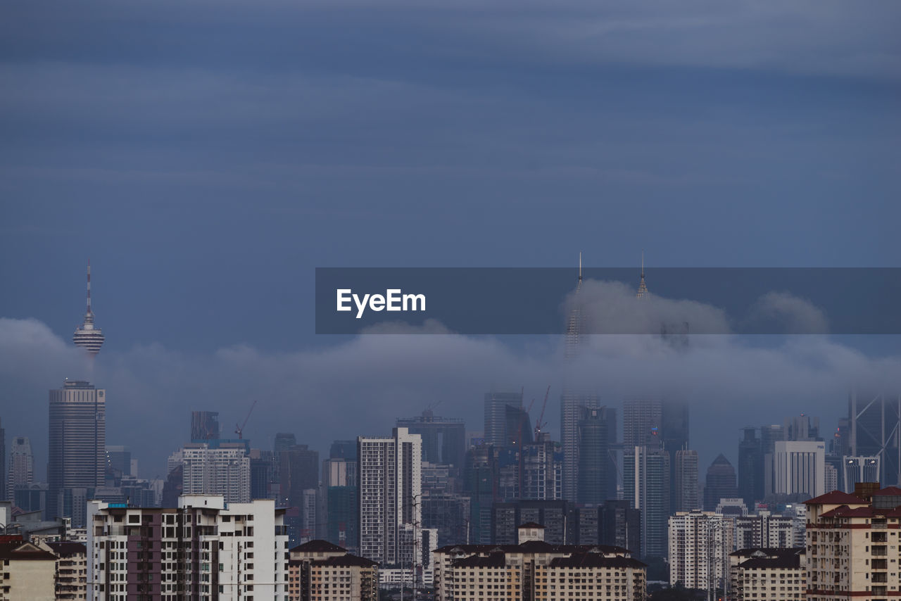 Buildings in city against cloudy sky