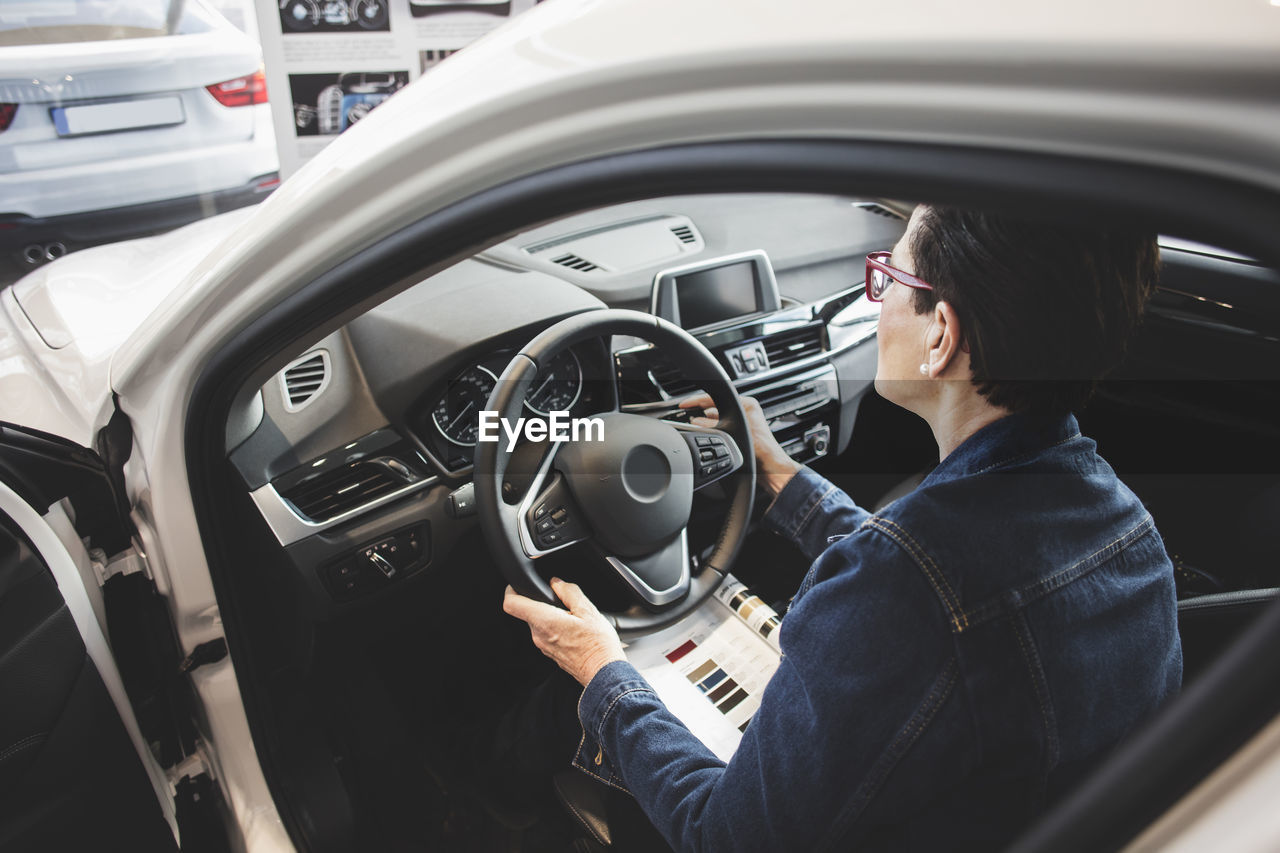 High angle view of senior woman examining while sitting in car