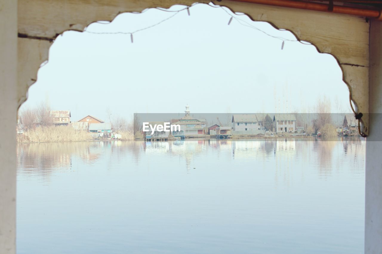 REFLECTION OF HOUSES IN LAKE AGAINST SKY