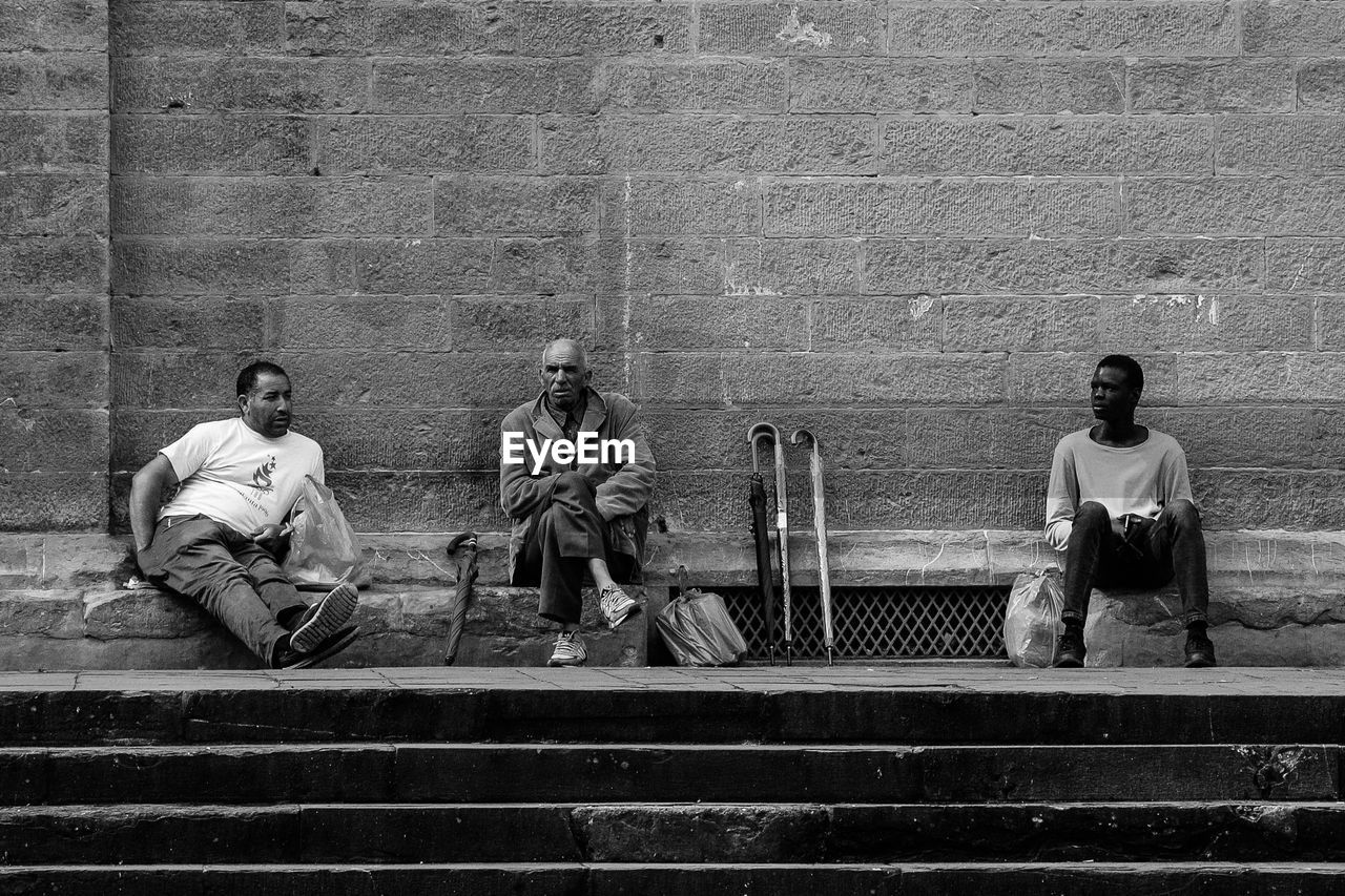 PEOPLE SITTING ON BENCH BY STAIRCASE