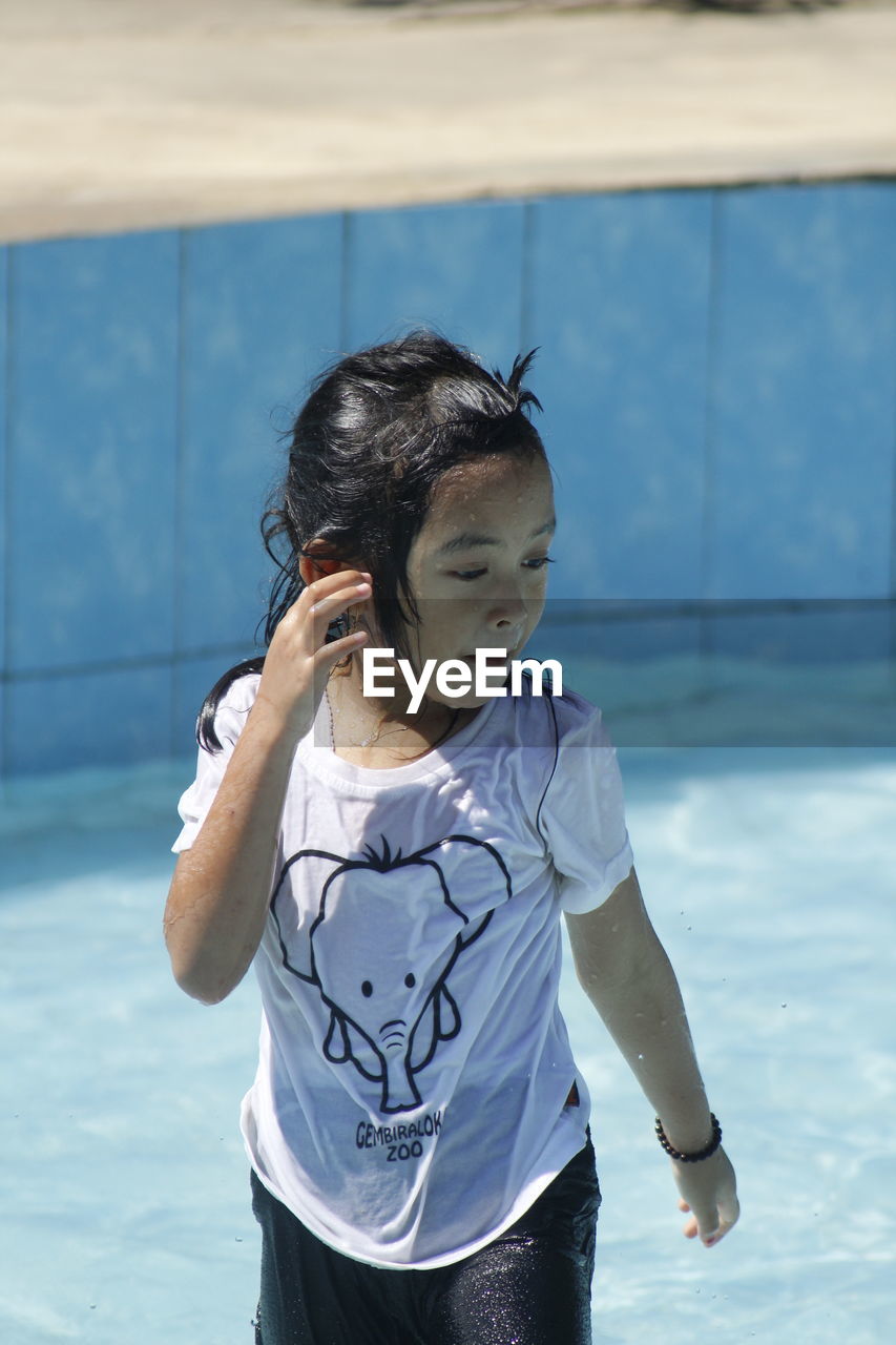 FULL LENGTH OF GIRL HOLDING SWIMMING POOL