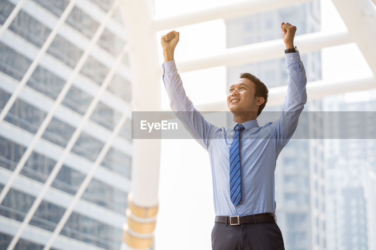 Smiling businessman standing in front of building