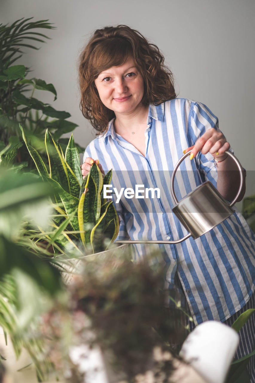 portrait of young woman standing by potted plants