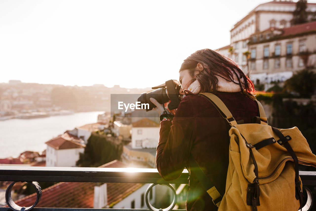 Woman in porto bridge taking pictures with camera at sunset. tourism in city europe. travel