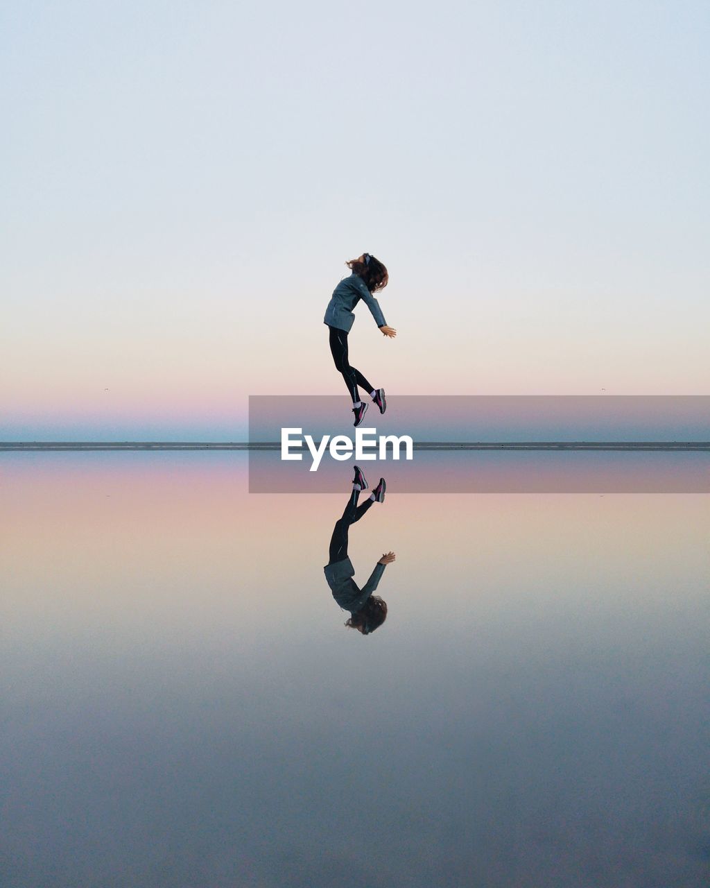 Full length of woman jumping on beach against sky during sunset