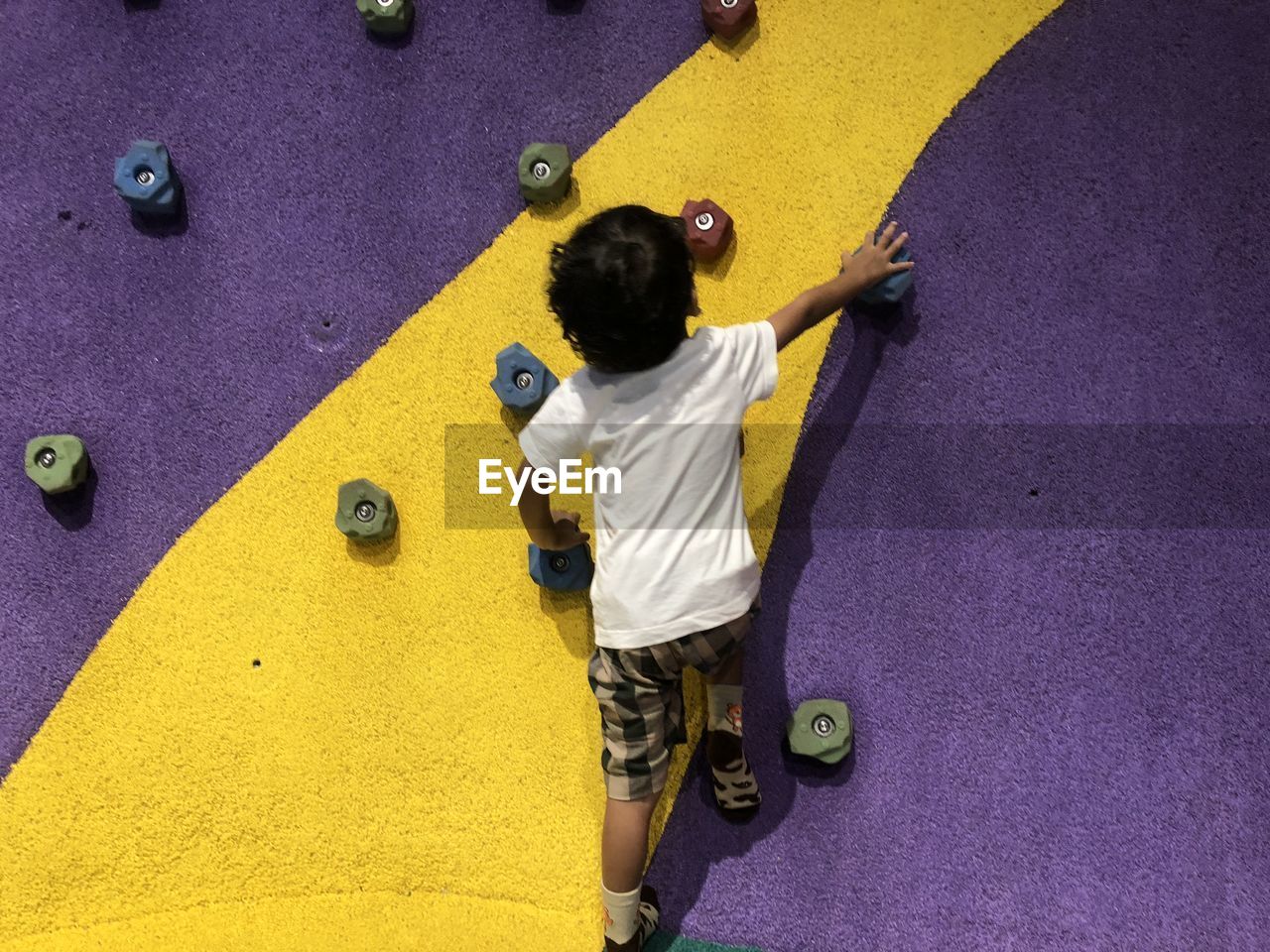 Rear view of boy climbing on wall