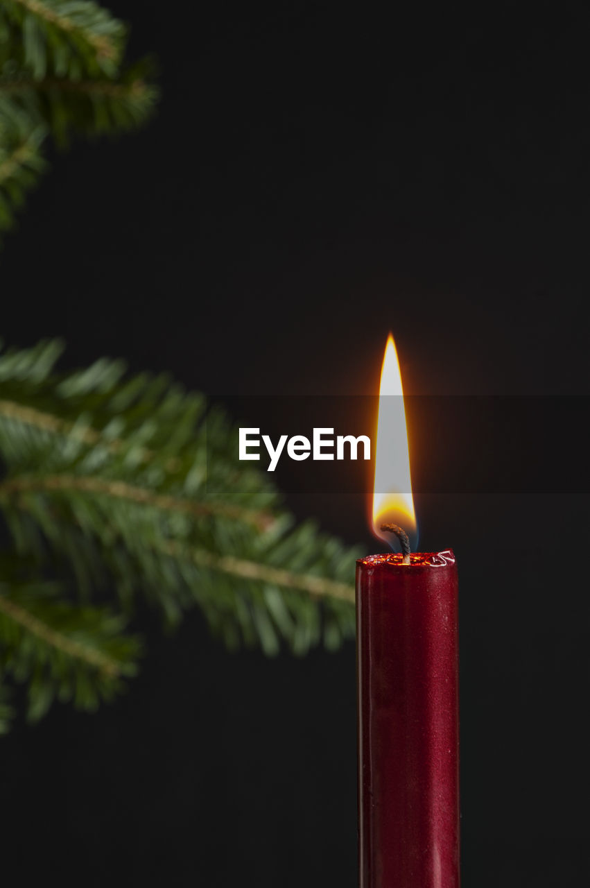 CLOSE-UP OF LIT CANDLE IN DARK