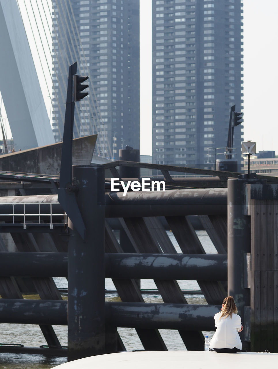 WOMAN SITTING AGAINST MODERN BUILDING